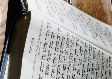 Close-up of a person reading a Hebrew book, highlighting religious study.